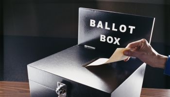 Man Inserting Voting Paper into a Ballot Box