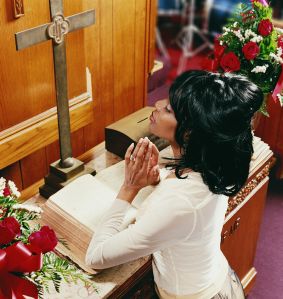 Young Woman Kneeling at an Altar in Church and Praying