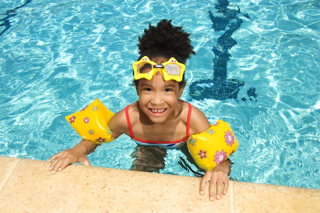 Girl with floaties and goggles in swimming pool