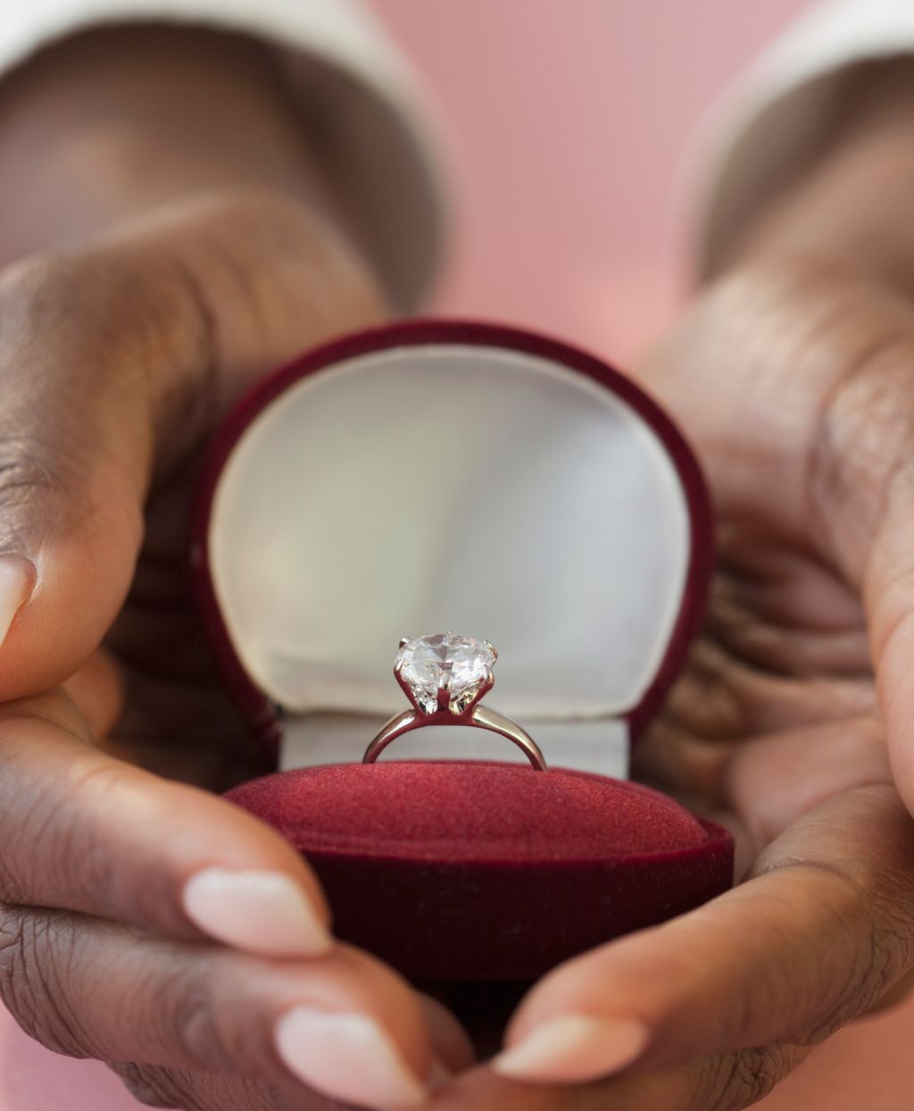 African woman holding engagement ring in box