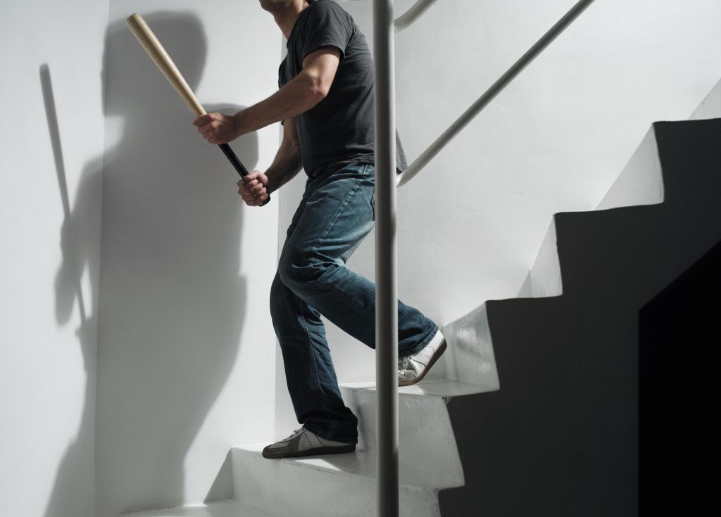 Man Holding Baseball Bat Going Downstairs