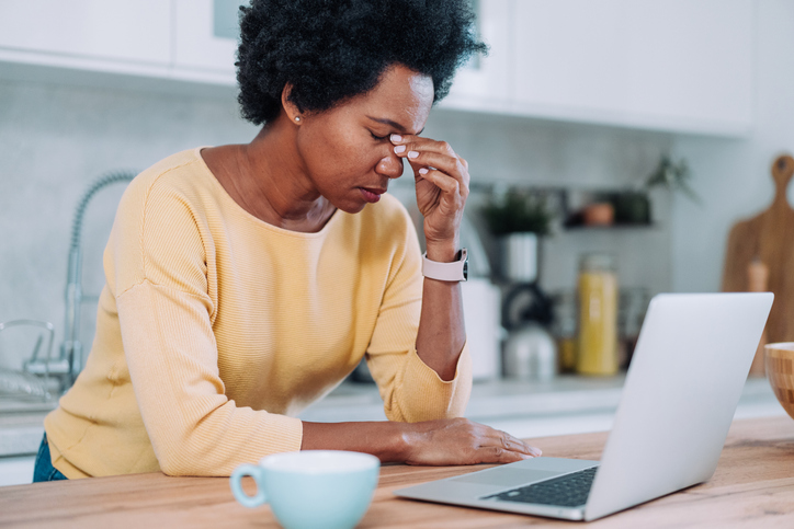 Stressed businesswoman having headache while working on laptop at home.